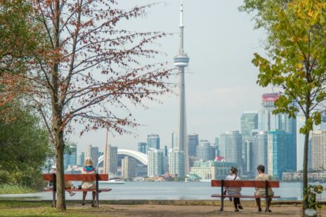 four-people-sits-on-park-benches-across-city-scape